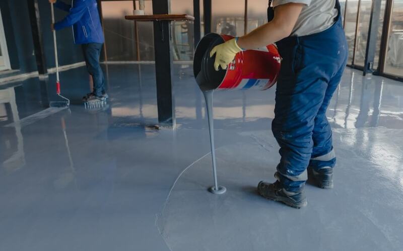 the-worker-applies-gray-epoxy-resin-to-the-new-floor-boots